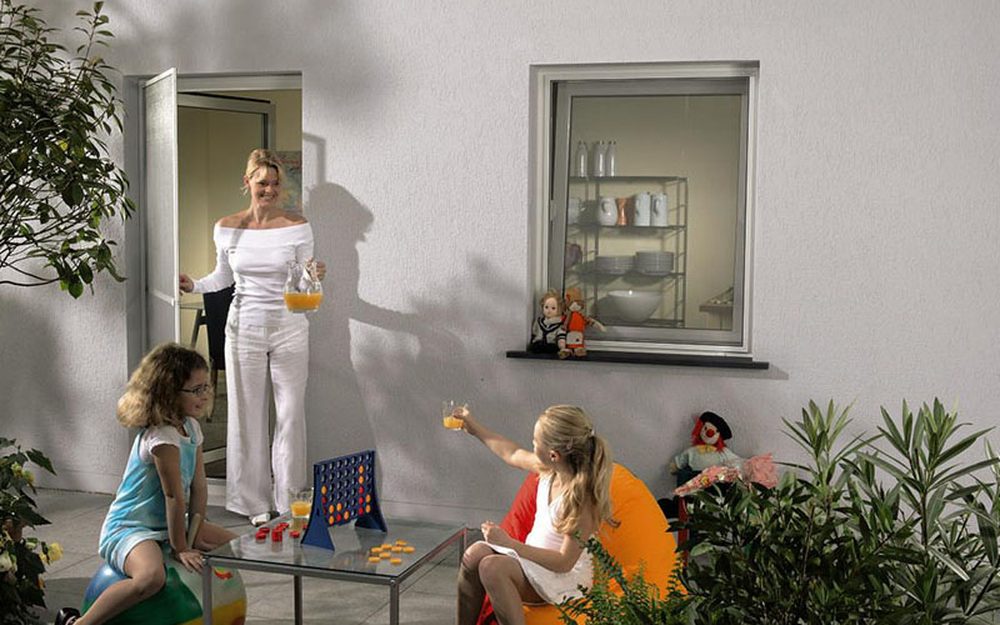 Familie auf einer Terrasse, im Hintergrund Fenster mit Insektenschutz